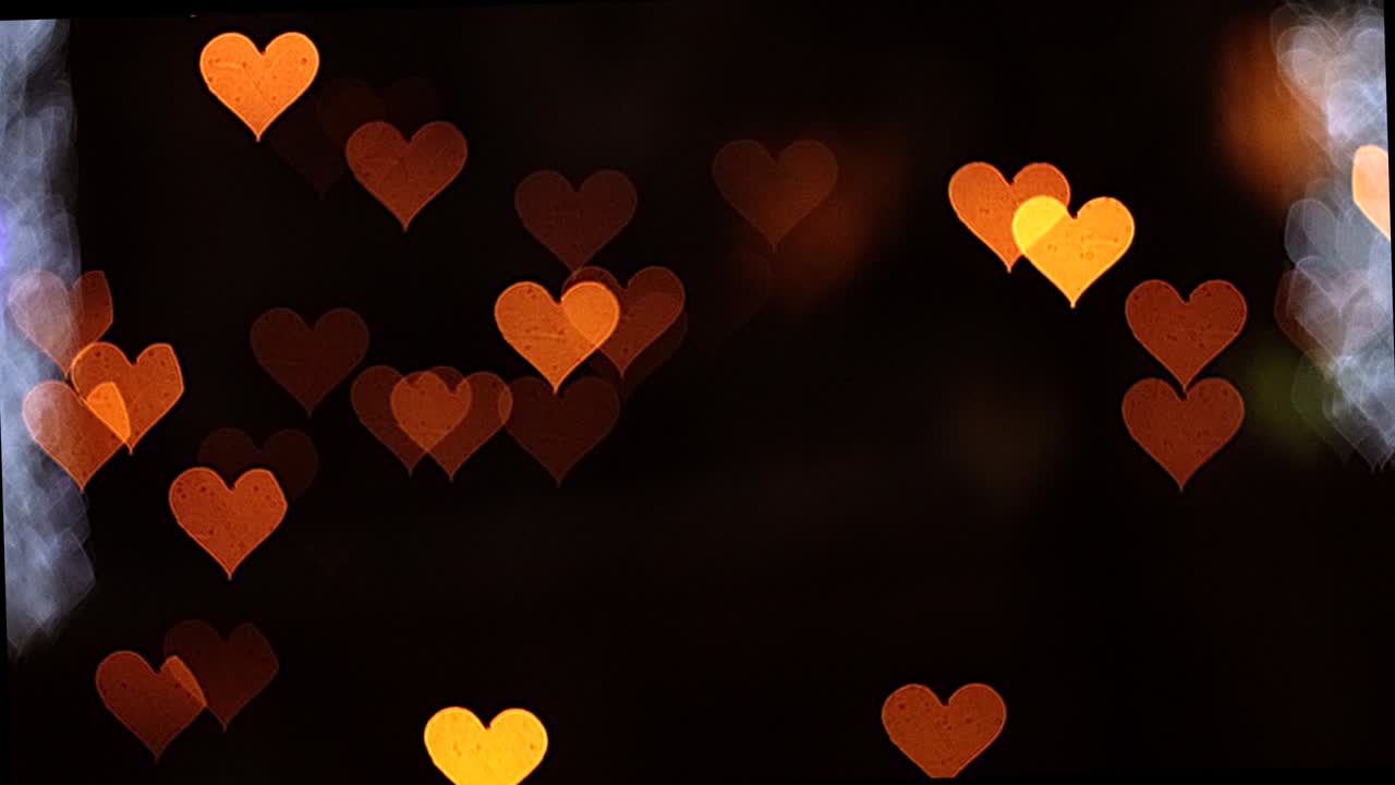 4k uhd video de fondo para el día de san valentín. frontera con bokeh de corazones románticos brillantes y relucientes en un fondo negro. amor, bokeh en forma de corazón.