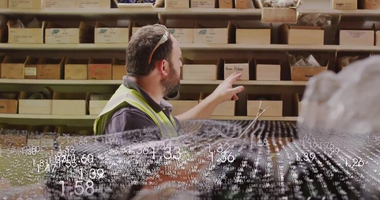 Addetto al magazzino legge un tablet, indica e conta i contenitori per le scorte, con un overlay di nuvola di punti in movimento.