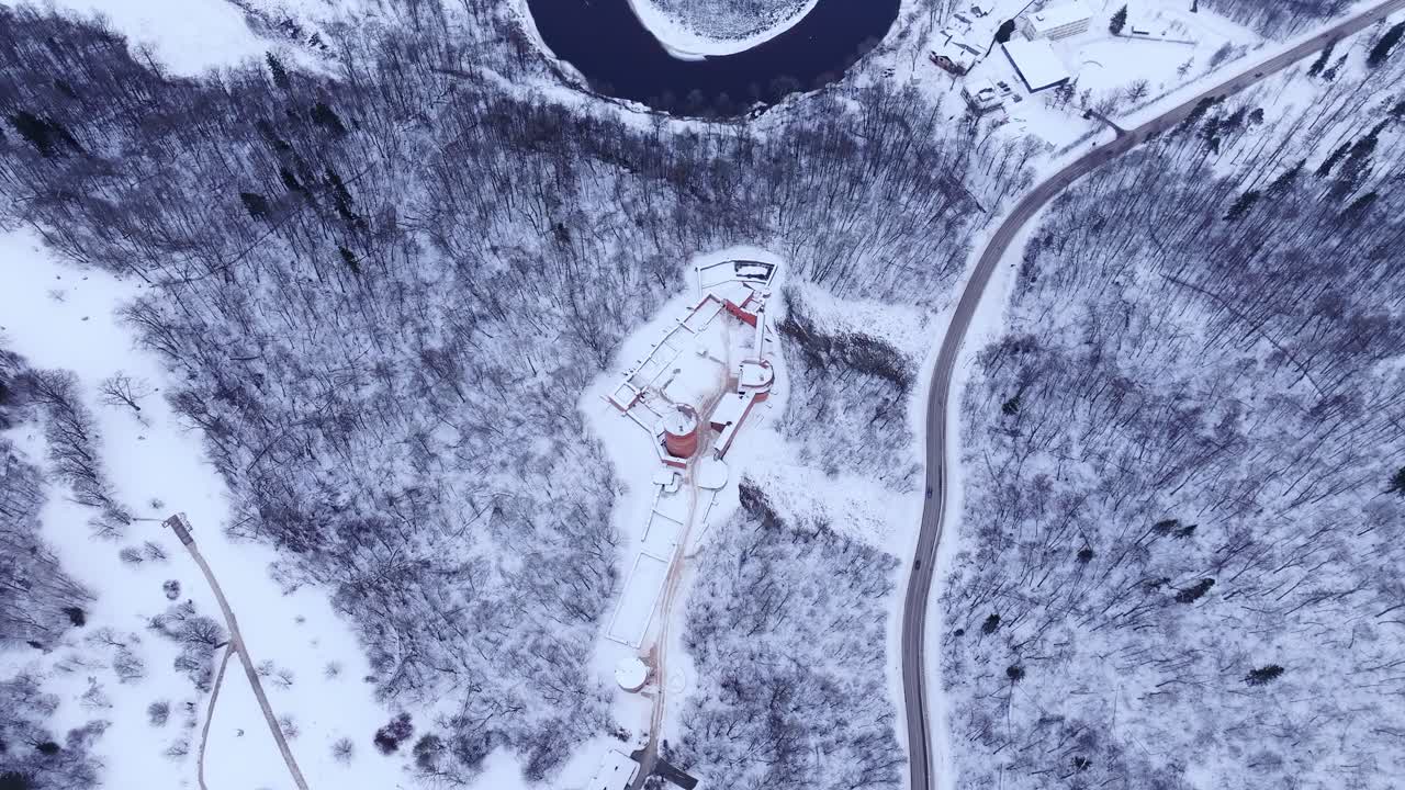 Aerial winter scene with white forests, castle towers and icy Gauja in Latvia