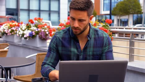 hombre de negocios tomando una taza de café mientras usa una computadora portátil