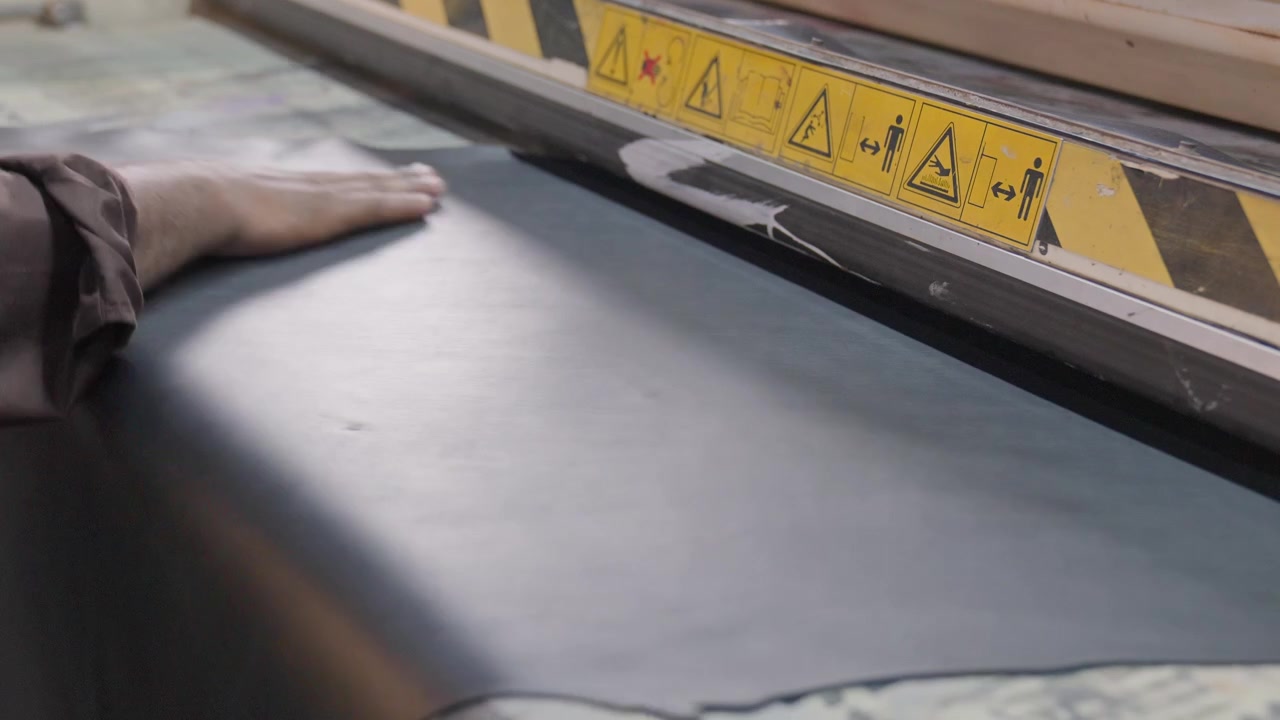 Arbejder forarbejder dyrehuder på en industriel produktionsmaskine på en læderfabrik, nærbillede