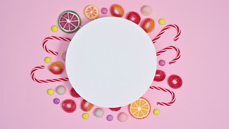 pastel pink background with sweets, candies and lollipops under paper card note. stop motion flat lay