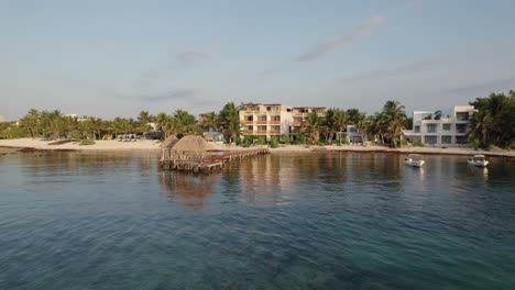 Aerial-pan-wide-shot-of-water-and-pier-dock-and-boats-passing-buildings-on-land