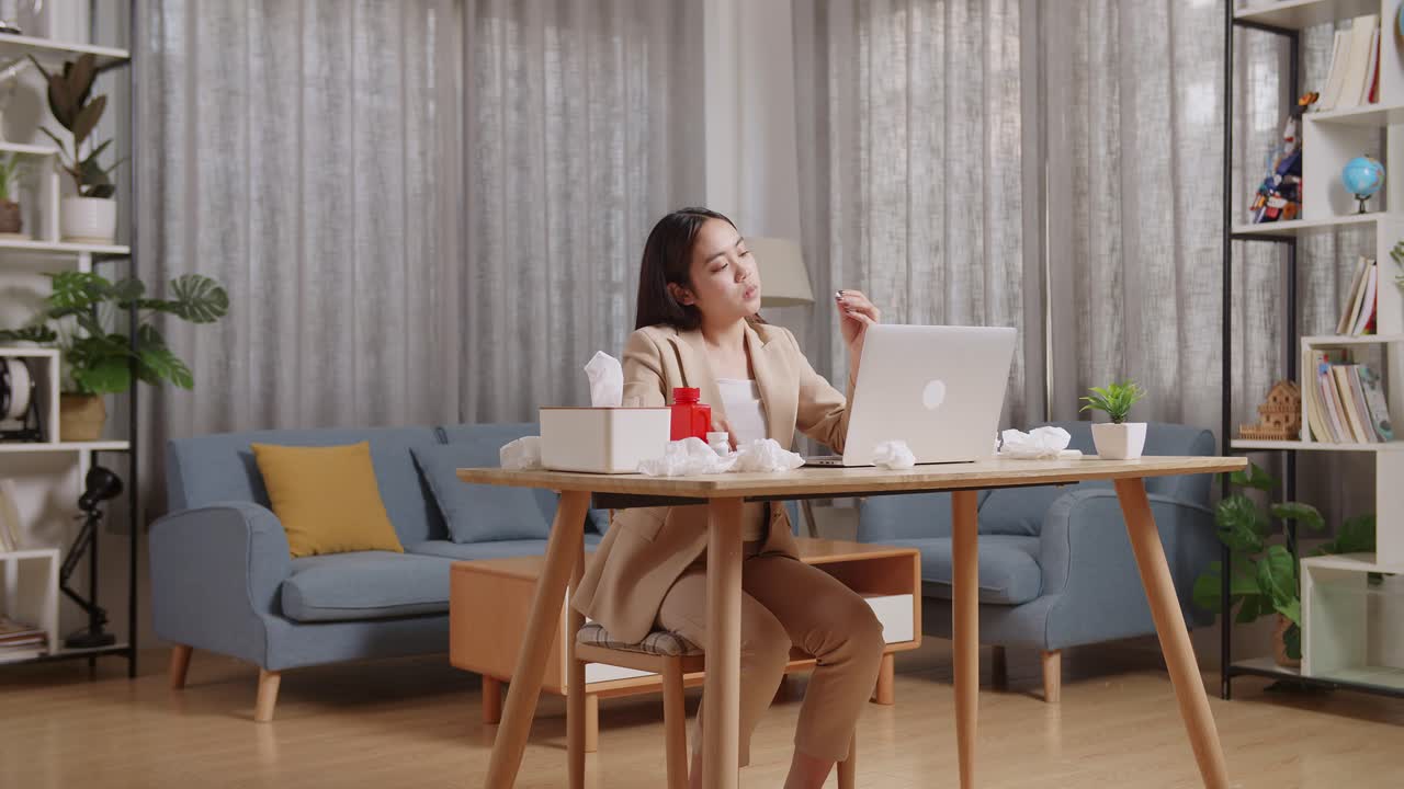 아픈 아시아 사업가 여성이 집에서 거실에서 노트북으로 일하면서 머리를 흔들고 있습니다.