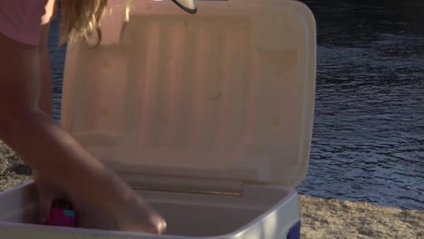 outdoor nature woman taking water bottle out of esky cooler box camping river australia