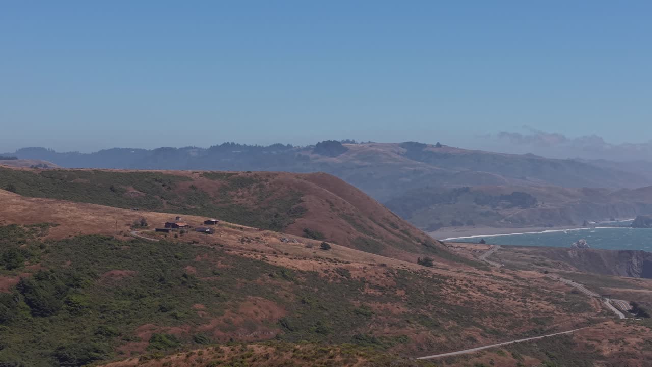 The drone glides along the shoreline, revealing textures in the rocky tide pools and coastal brush