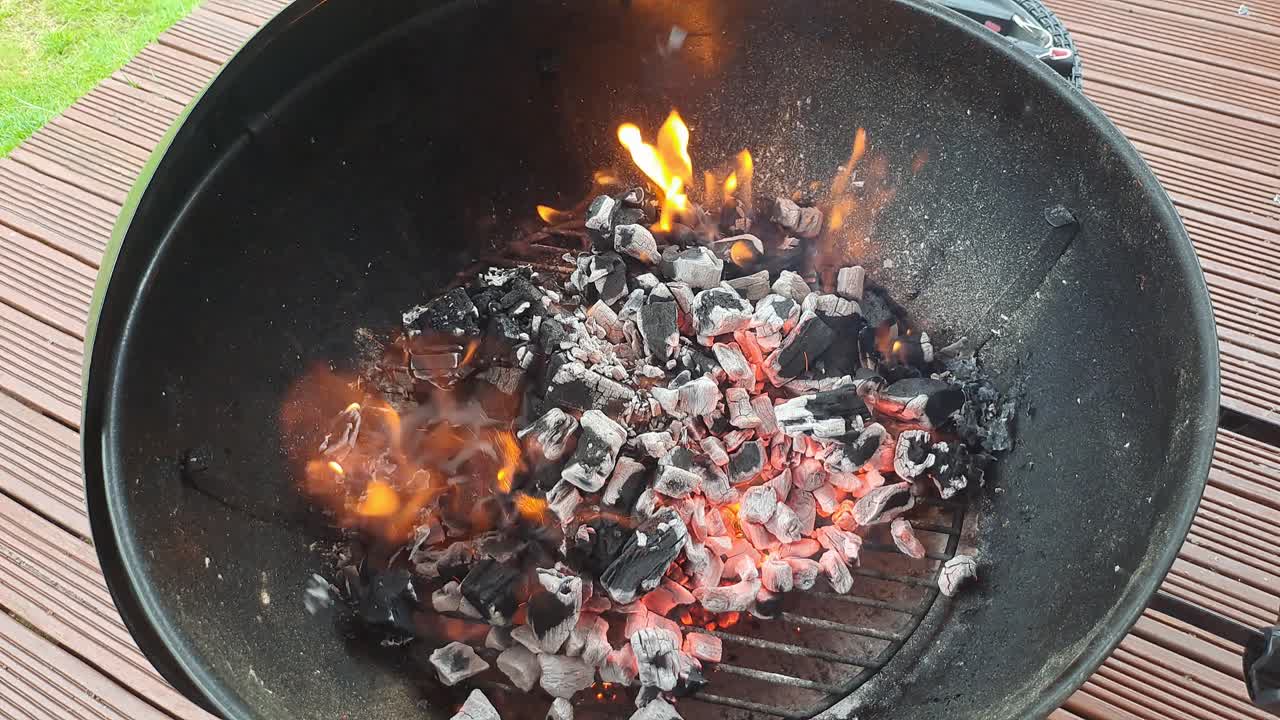 Brennende grillkull for å tenne bålet, klart for matlaging.