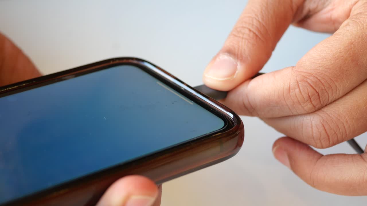 Primo piano di una mano che collega un cavo di ricarica a uno smartphone