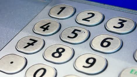 primer plano de un panel de teclado de atm de acero y una mano masculina escribiendo un código pin