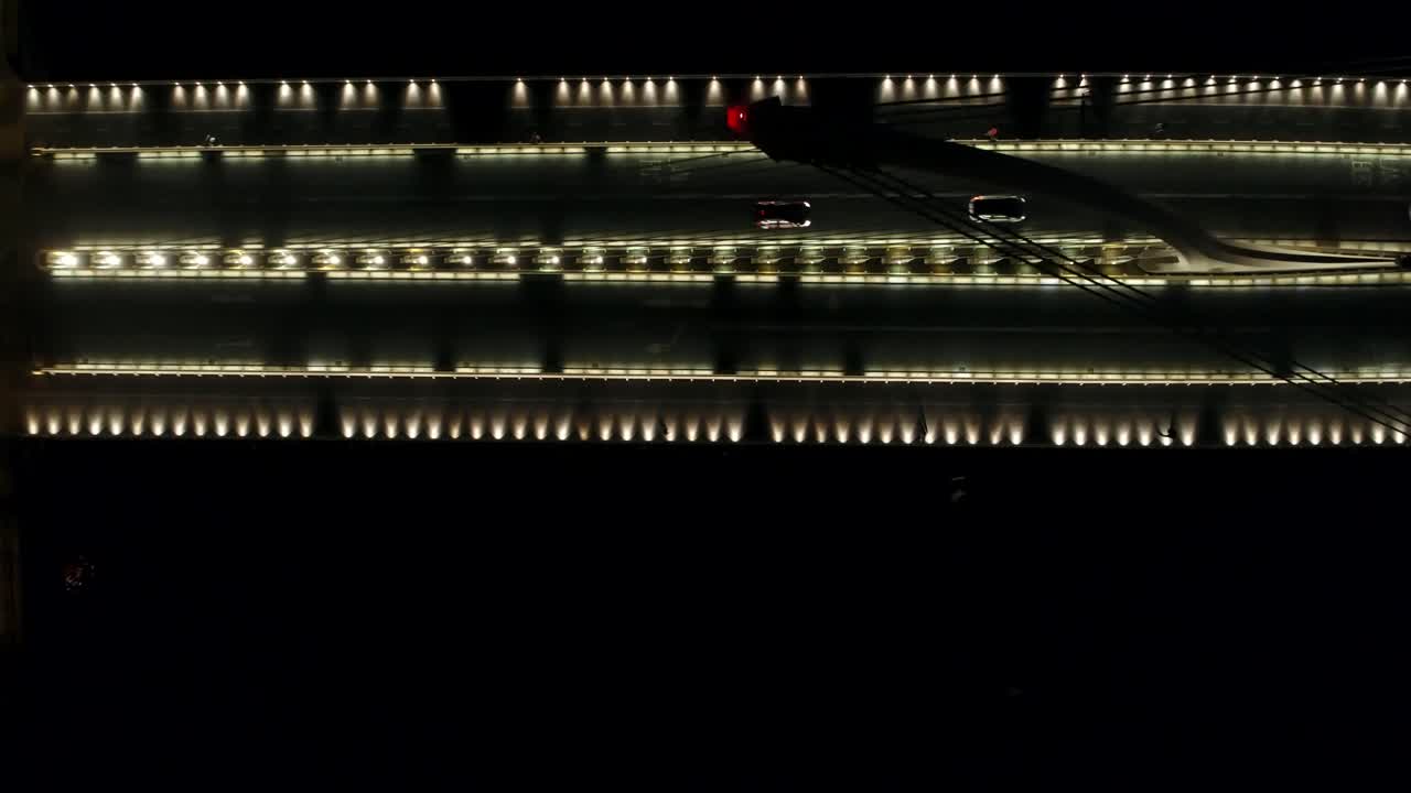 Birds eye view as we fly over an illuminated Samuel Beckett bridge over the River Liffey in Dublin in the still night.
