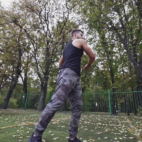 healthy athlete doing his workout outdoors. sportive man is exercising on the stadium near the autumn park. slow motion.