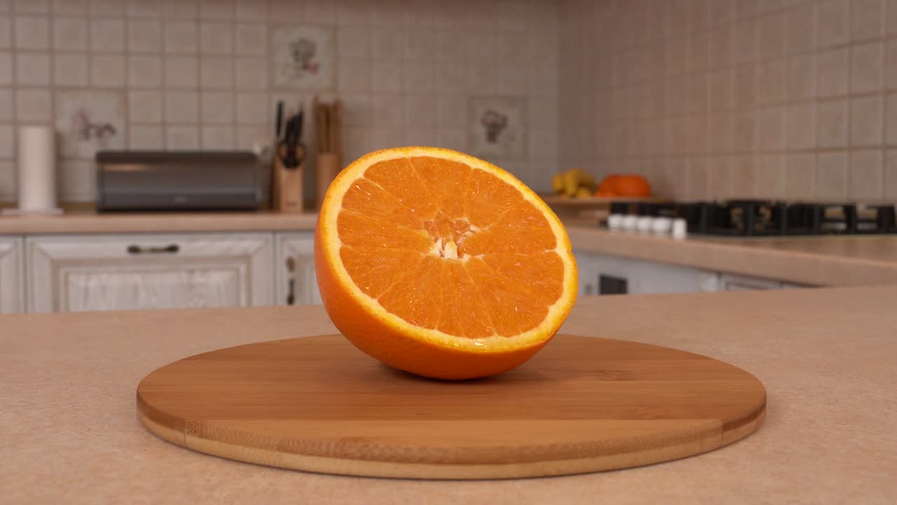 un primer plano de frutas de naranja en rebanadas. la mitad de una naranja. cámara giratoria con cocina blanca en el fondo. dolly-shot.