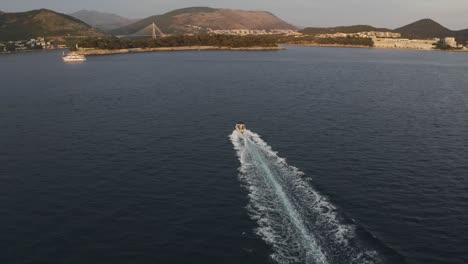 A-speedboat-speeds-across-the-Adriatic-sea-near-Dubrovnik,-Croatia---Aerial