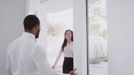 Man-Opens-Front-Door-Of-House-And-Hugs-Business-Wife-Returning-Home-From-Work