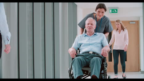 nurse pushing senior patient in wheelchair along corridor