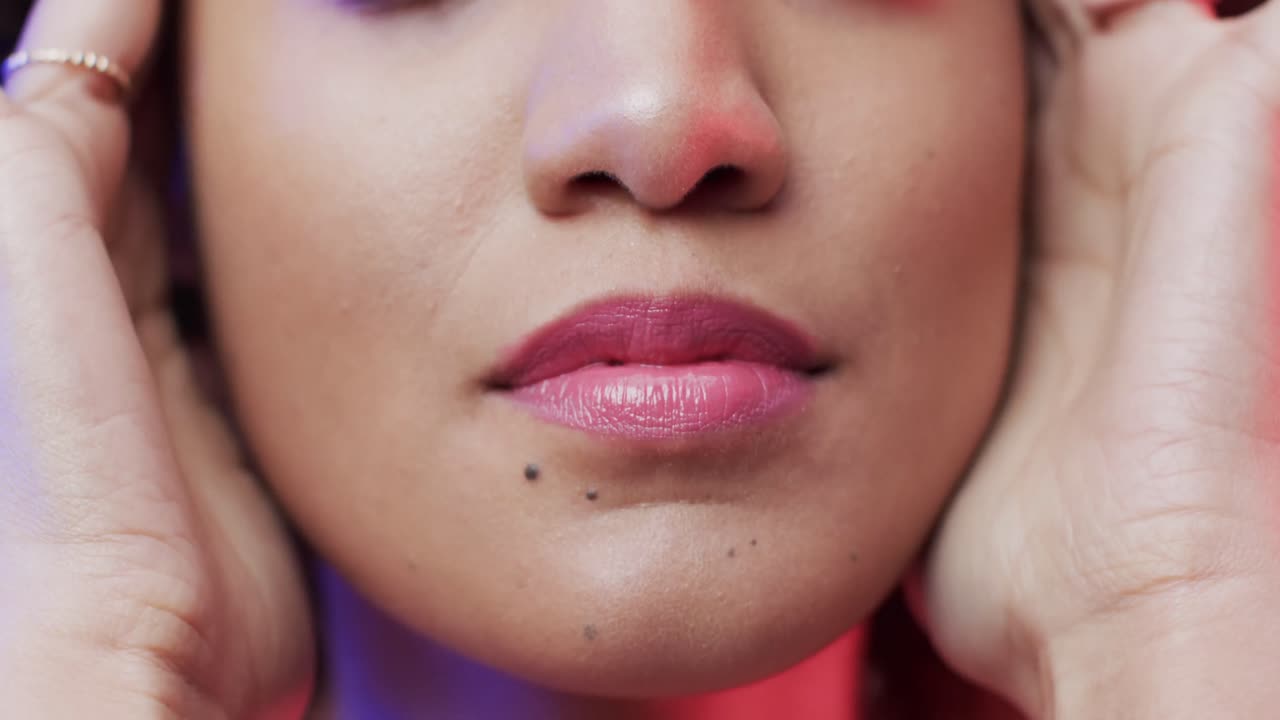 primer plano de una mujer biracial con cabello rizado oscuro en luz azul y rosa, cámara lenta