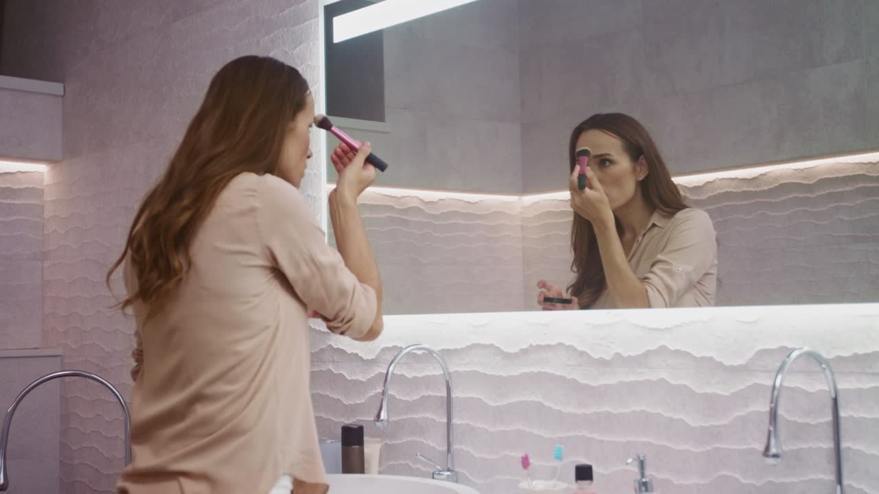 mujer de belleza haciendo maquillaje en el baño. mujer feliz haciendo maquillaje matutino.