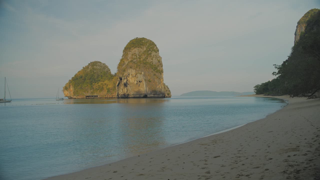 спокойные морские воды на отдаленном пляже на железной дороге с скалой на заднем плане