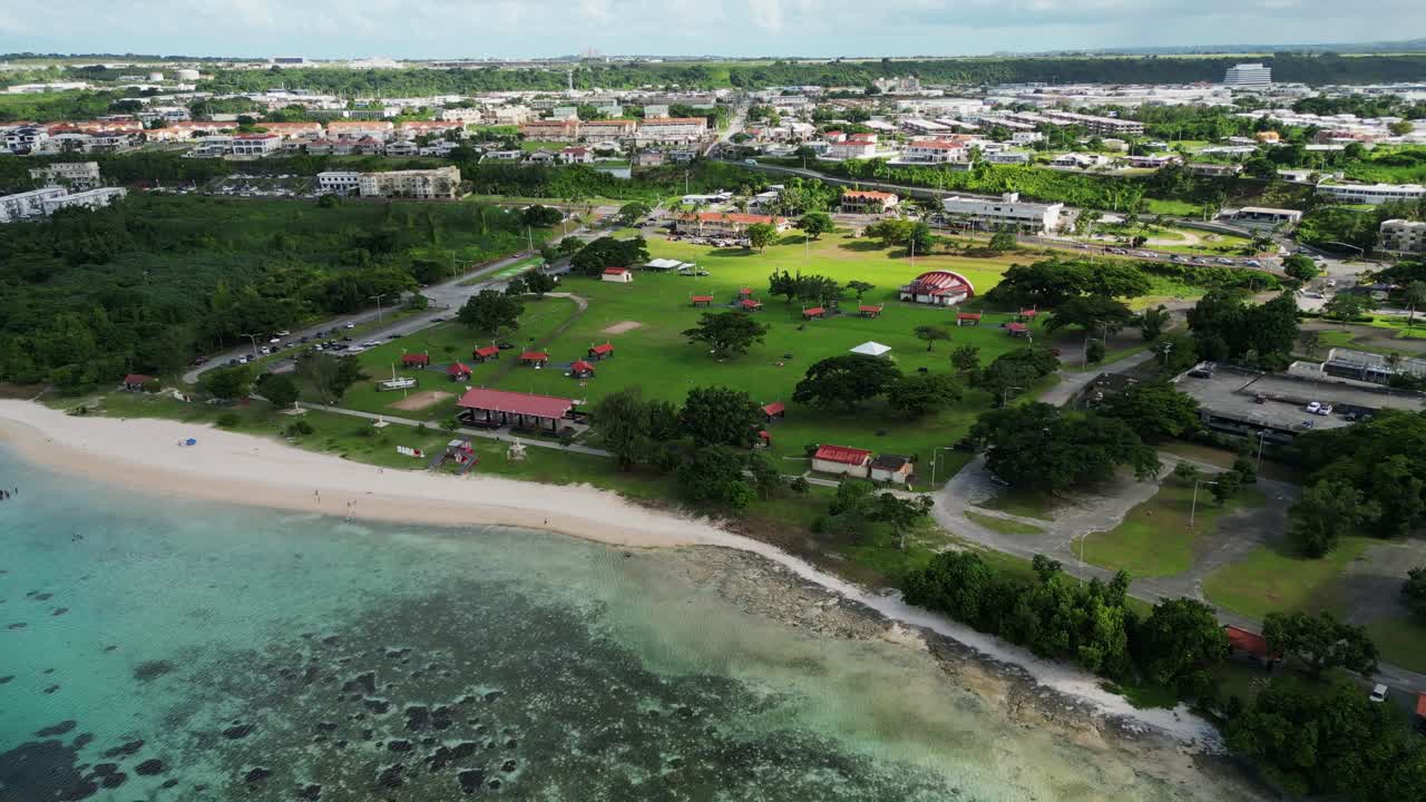 Scenic aerial pullback of Ypao beach park with lush scenery and white sand beach during daytime at Tamuning, Guam, USA