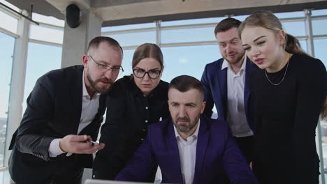 office people discussing something emotionally looking at laptop. business team shocked with information on computer screen.