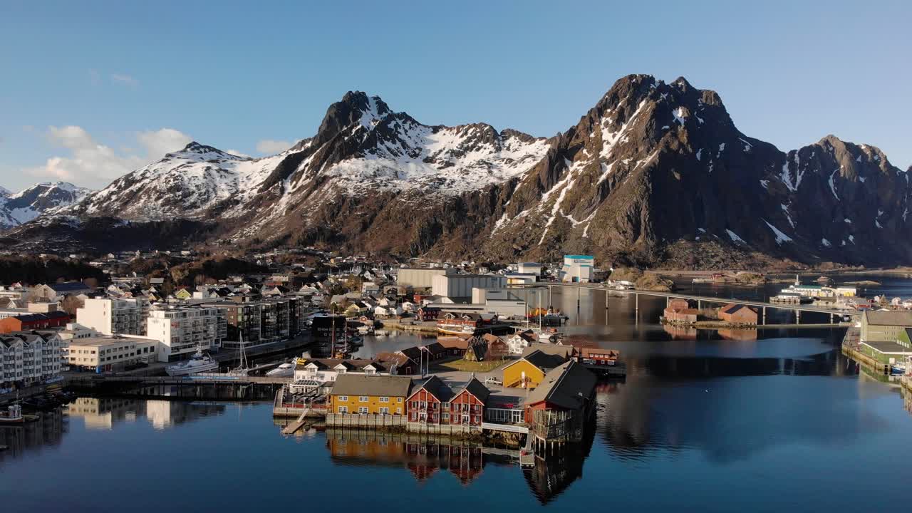 Aerial drone shot of a small town in Lofoten, Norway with a big mountain chain in the background