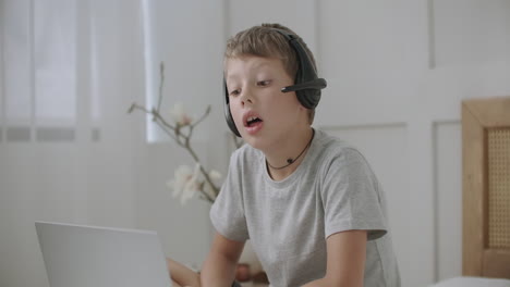 calm schooler boy is drawing alone in his room viewing cartoons by laptop with headphones entertaining independently