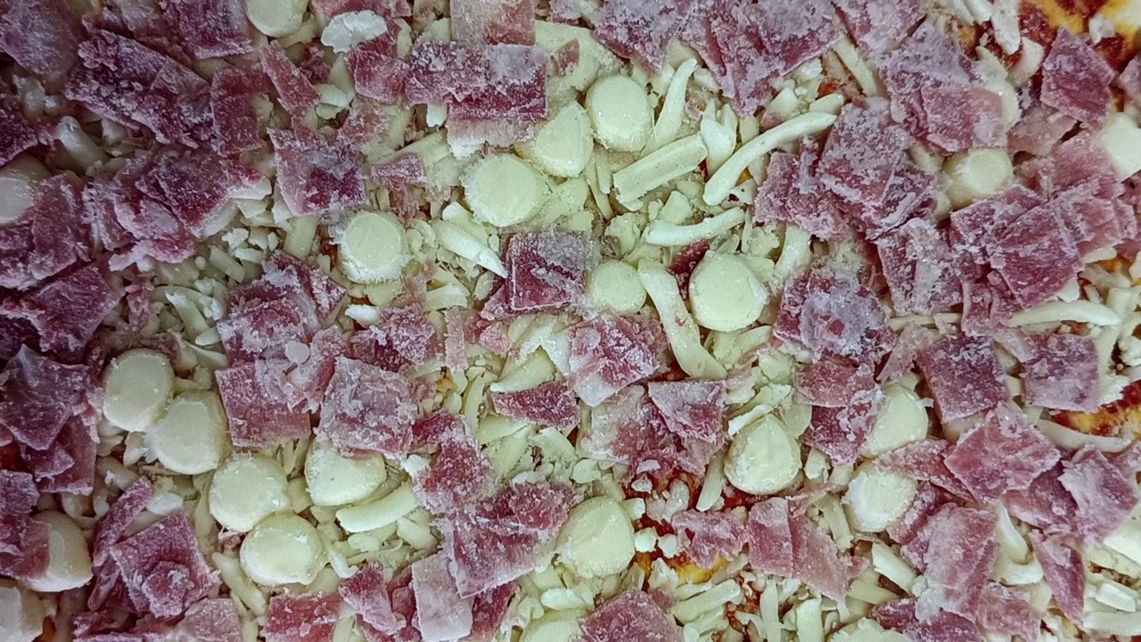 Mražená pizza v rotaci, detailní záběr.