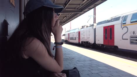 woman waits pensively as train passes in belgium