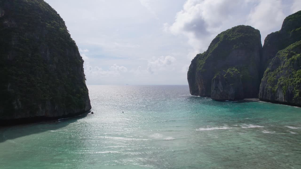 aerial view from the Maya Bay tropical sandy beach with turquoise water ocean on Phi Phi islands, Krabi, Thailand with nobody. Empty beach, surrounded by towering green cliffs under bright blue sky
