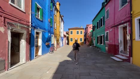 caminando por burano: jóvenes turistas se maravillan de las coloridas calles y la historia de la pintoresca isla de venecia