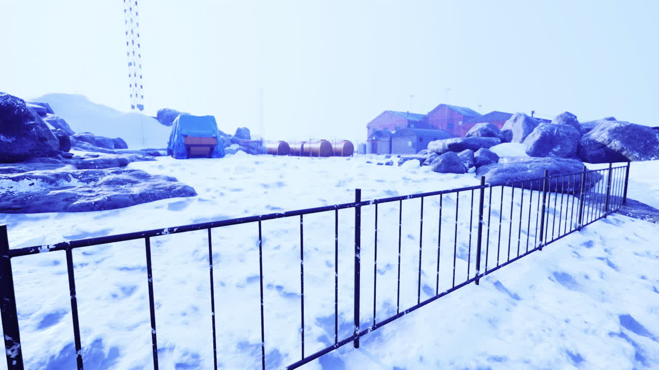 Snow covered landscape with fences and structures in a remote area