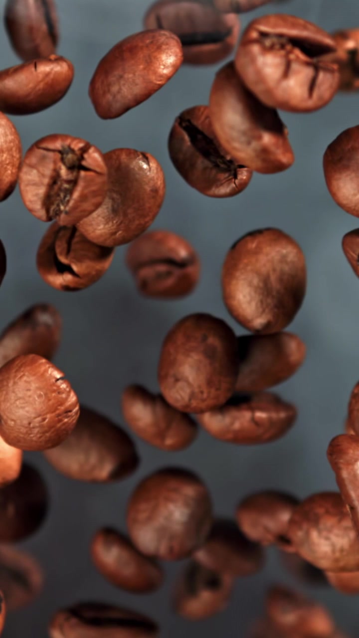 Chicchi di caffè tostati in caduta al rallentatore con transizione di messa a fuoco