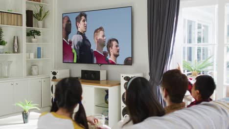 행복 한 가족 이 집 에서 함께 앉아 tv 에서 스포츠 이벤트 를 시청 하고 있는 사진