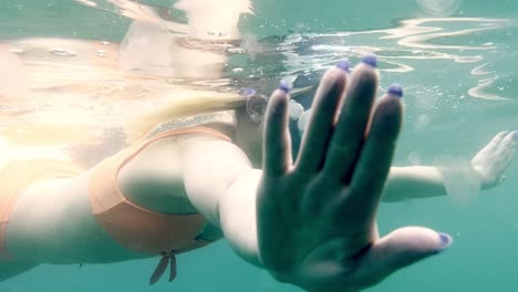 a person swimming under the turquoise water with diving glasses