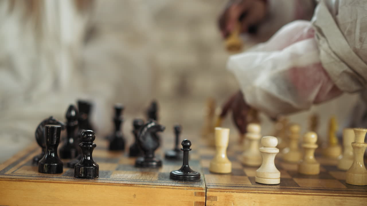 Player arm positioned over chessboard making thoughtful move with white piece during competitive match, surrounded by black and white chessmen