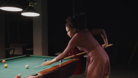 woman playing pool in a dark room