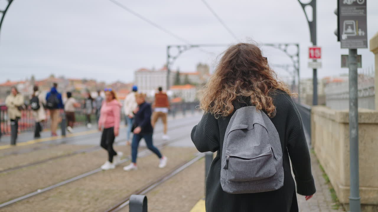 mujer con mochila caminando por un puente de la ciudad