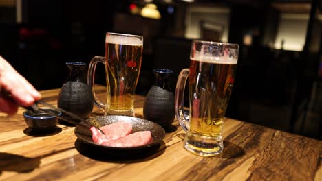 beer poured into glass, beef cooked on hot stone.