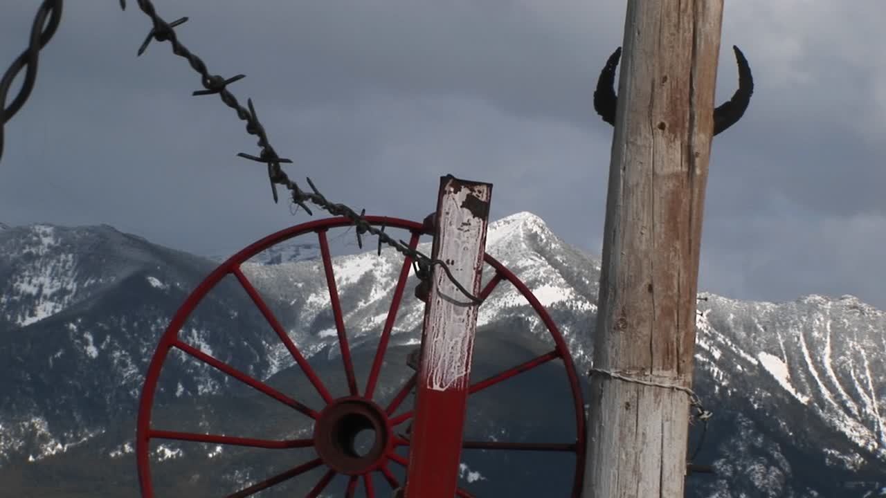средний снимок западных гор красный обод колеса повозки колючая проволока и рога скота, привязанные к столбу