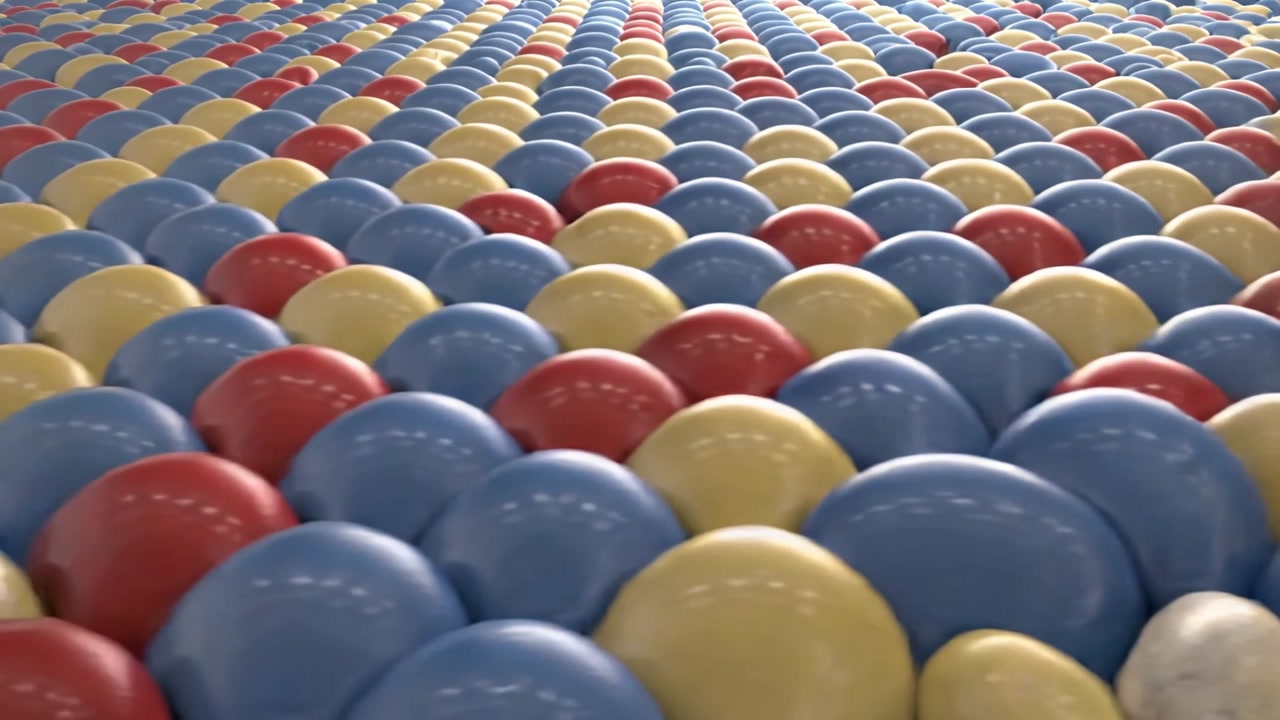 Gliding camera moving over ballpit in hall nudging glossy primary and white balls revealing rolling