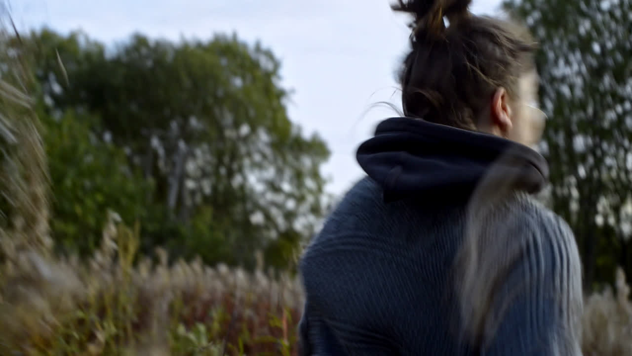 Moving and dynamic frame with young and happy woman running through the meadow.