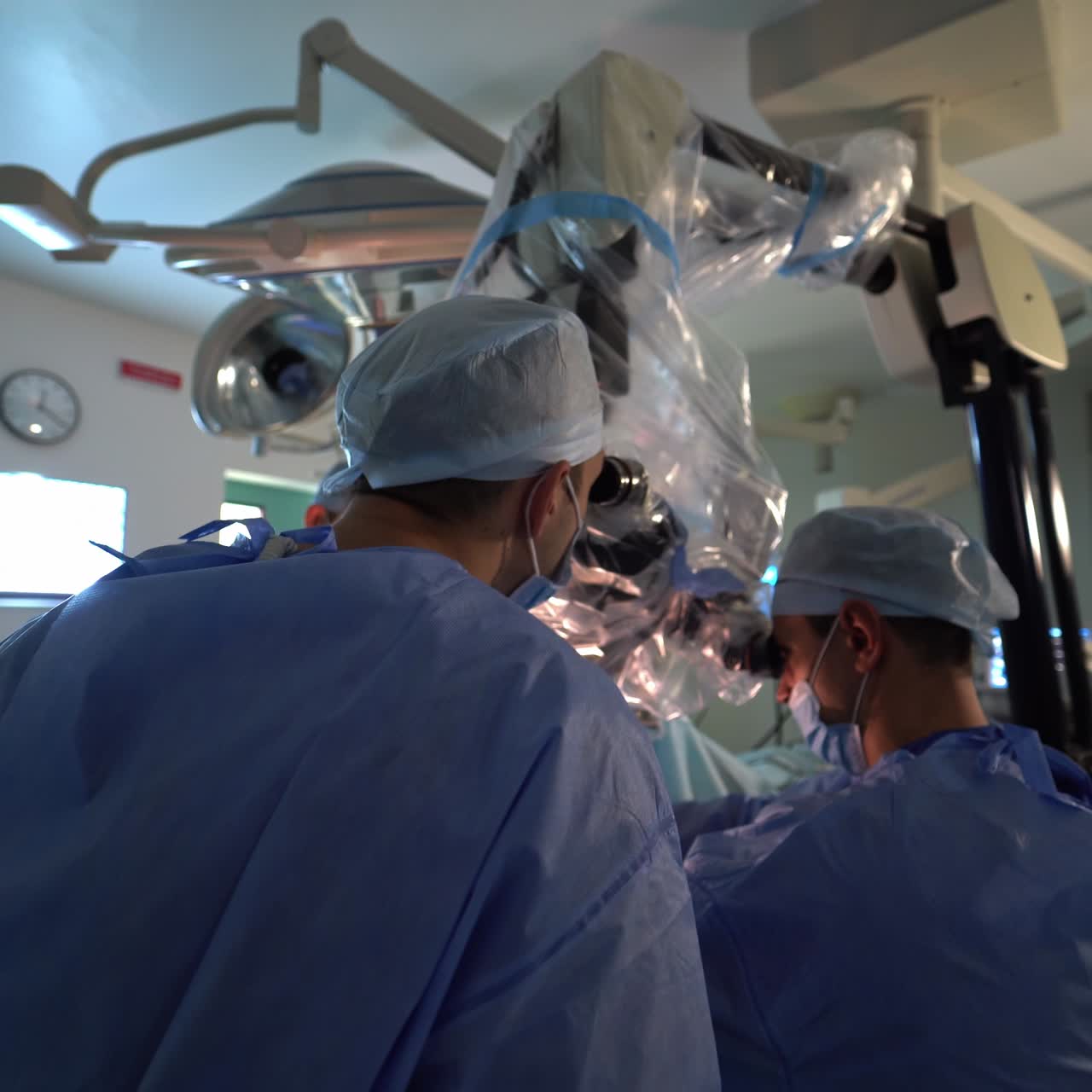 Two neurosurgeons having operation with the help of a powerful microscope. Hi-tech instruments for neurosurgical operations. Circle motion around the doctors