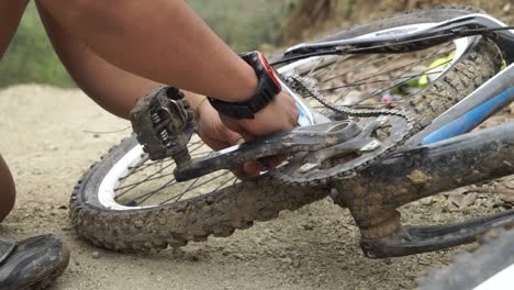 cyclist repairing his chain of his mountainbike during a race with his hands on a dirt road in equador close up shot 50fps