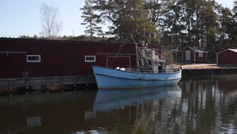 tilt shot from brown river to old fishing boat in sweden, europe on sunny day