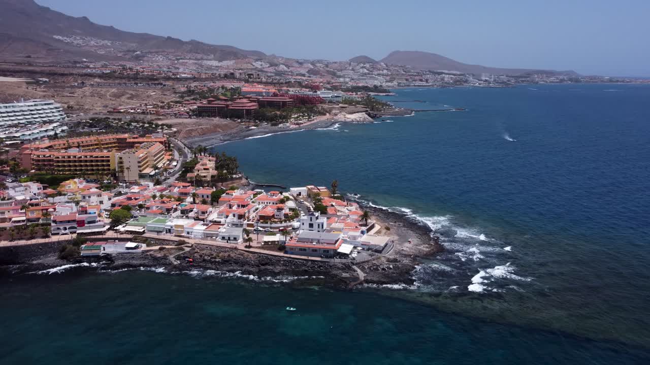 Drone view of small village and the coast by the ocean with mountains in the background in La Caleta, Tenerife, Canary Islands, Spain.