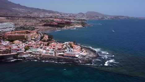 drone view of small village and the coast by the ocean with mountains in the background in la caleta, tenerife, canary islands, spain.