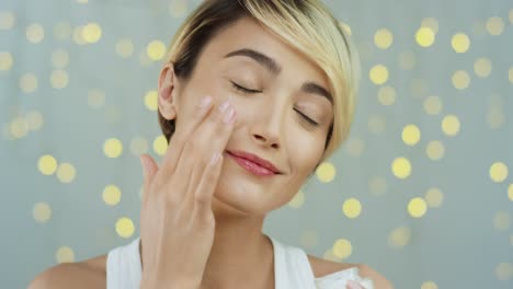 Close-Up-Of-The-Middle-Aged-Good-Looking-Woman-With-Smooth-Skin-Moisturaizing-Face-With-Cream-And-Smiling-To-The-Camera