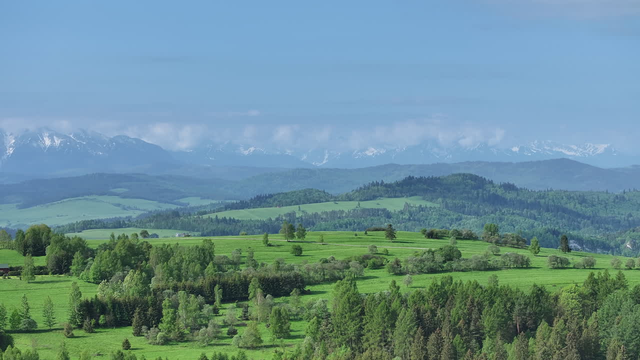 beauty of nature as morning fog gently blanketing the lush green hills and meadows, creating a serene and cinematic landscape with high mountain range towering in the back.