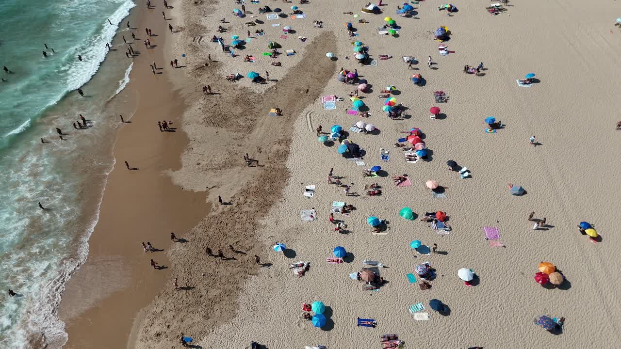 Aerial view of a crowded beach with people and umbrellas