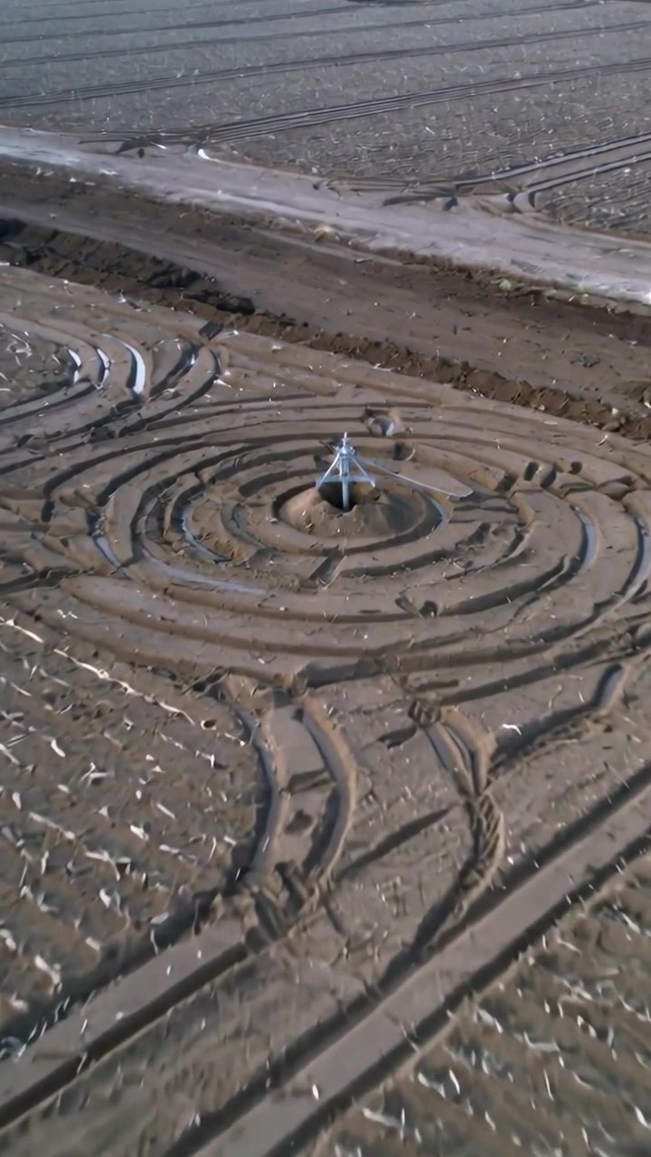 Vertical video: Moving camera closing on metal tripod in harvest field to reveal concentric rings